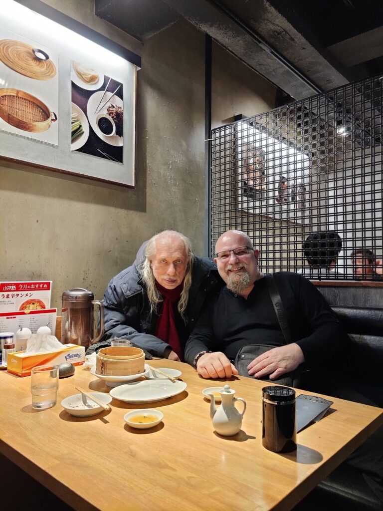 Zwei Männer sitzen nebeneinander am Restauranttisch in Tokio