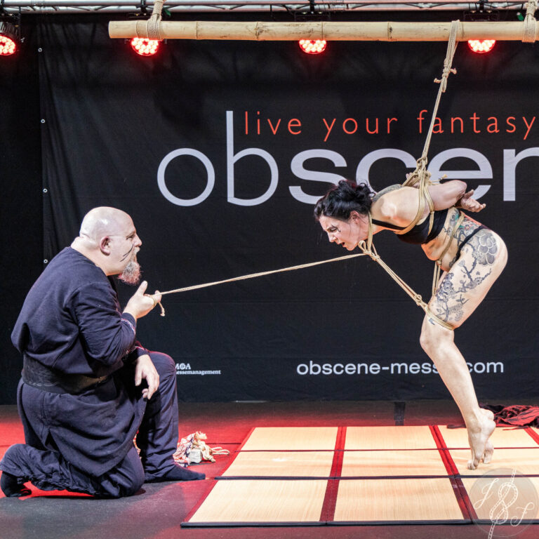 Bühnenperformance auf der obscene 2023: der Rigger führt das Model am Seil