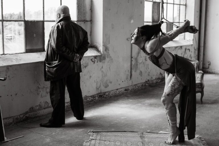 Gebeugte Fesselung am Fenster einer Fabrikhalle, schwarzweiß