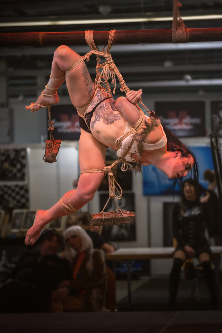 Hängefesselung in Seitenlage mit Gewichten an den Seilen auf der Bühne der Bondage-Fetish-World