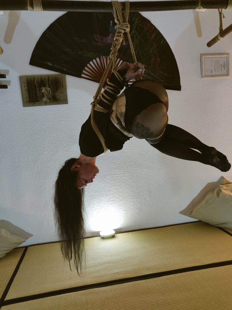 Kopfüber-Hängefesselung vor einem Fächer