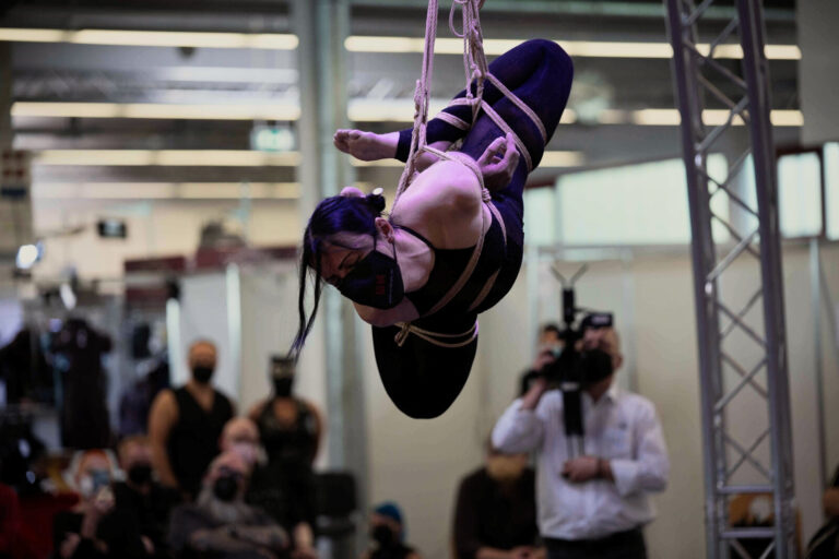 Kopfüber-Hängefesselung in kompakter Haltung bei einer Bühnenshow auf der Bondage-Fetish-World 2021