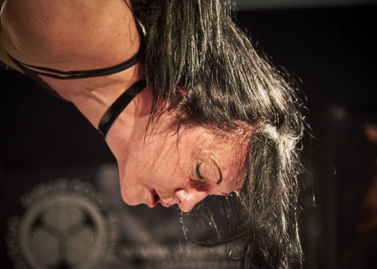 Nahaufnahme: das Gesicht des Models kopfüber in der Hängefesselung, BoundCon 2018