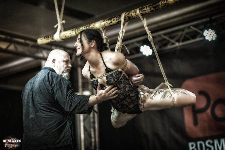 Teilhängefesselung im Spitzenbody, Rigger und Model sehen sich an, Passion 2021
